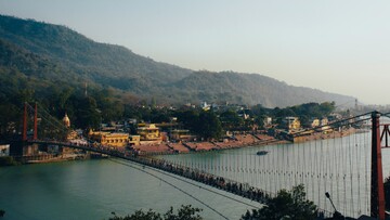 people crossing river in rishikesh on a bridge