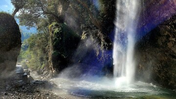 serene waterfall streaming through rocks and trees in chakrata