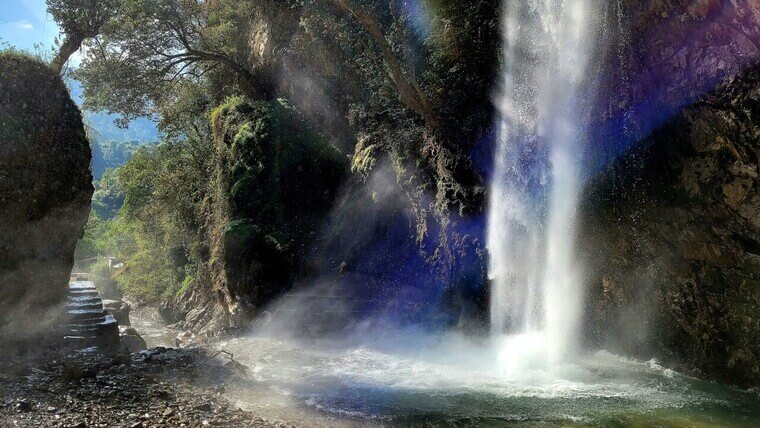 serene waterfall streaming through rocks and trees in chakrata