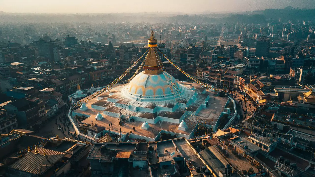 Aerial view of a spacious Buddhist temple, featuring ornate structures and vibrant gardens in the surrounding area.