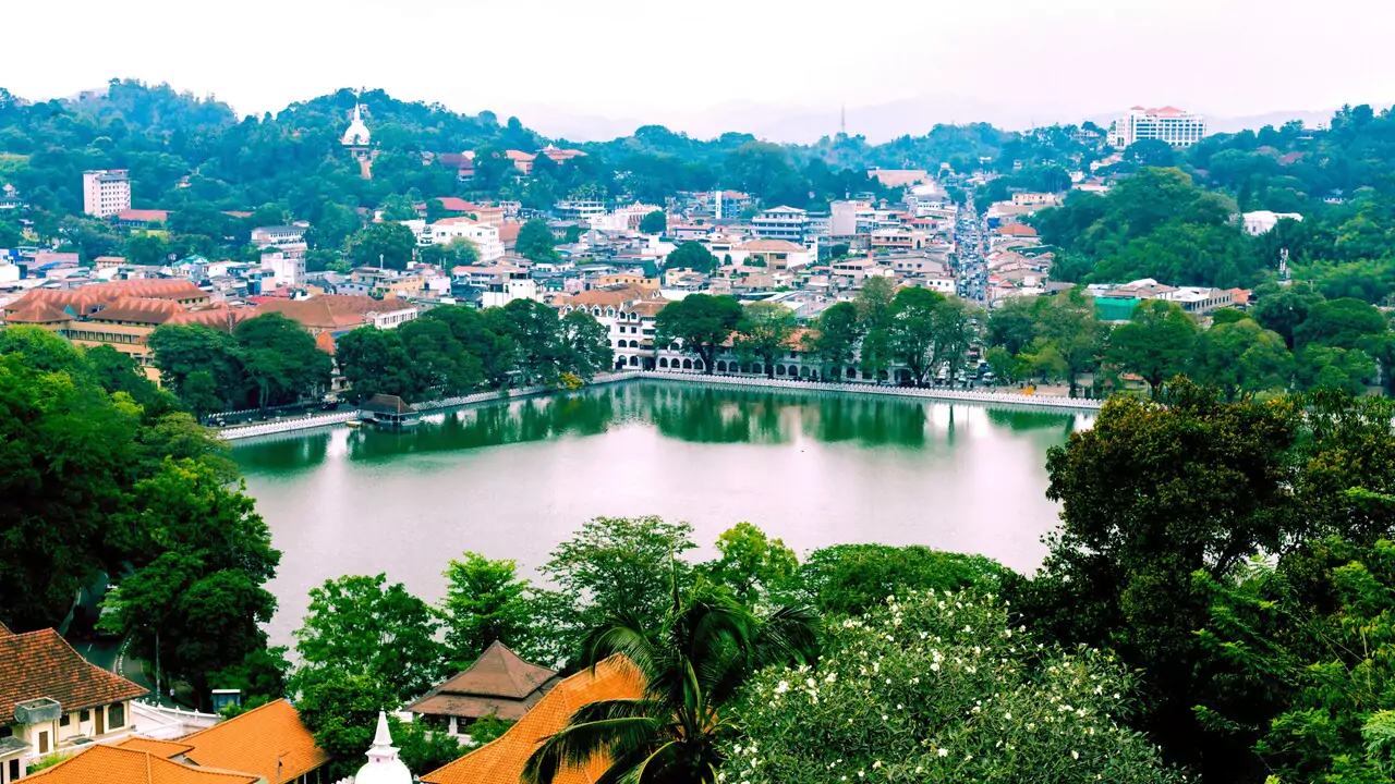 Hilltop view of Kandy city, featuring a mix of urban structures and lush greenery.