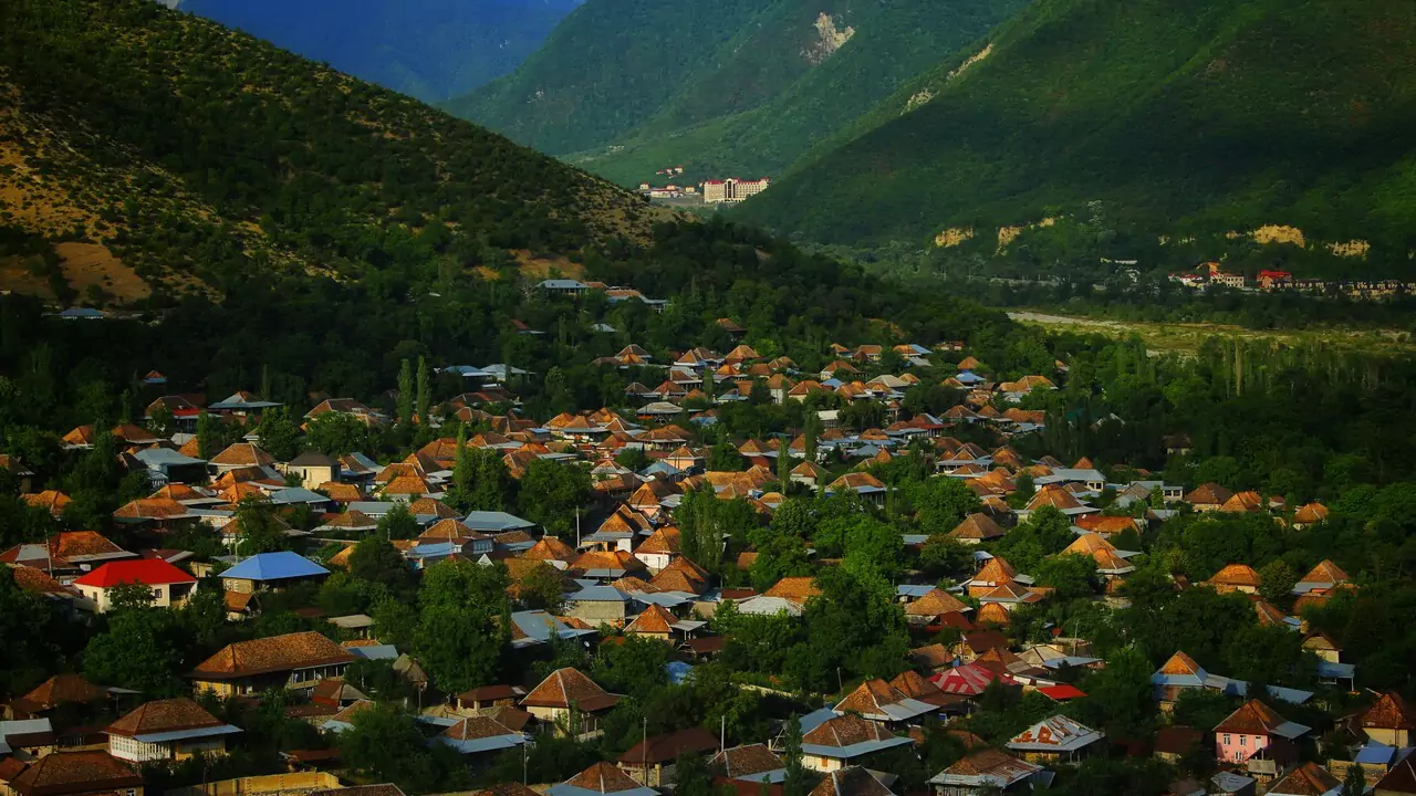 A charming mountain village with a cluster of houses set against a backdrop of towering peaks.