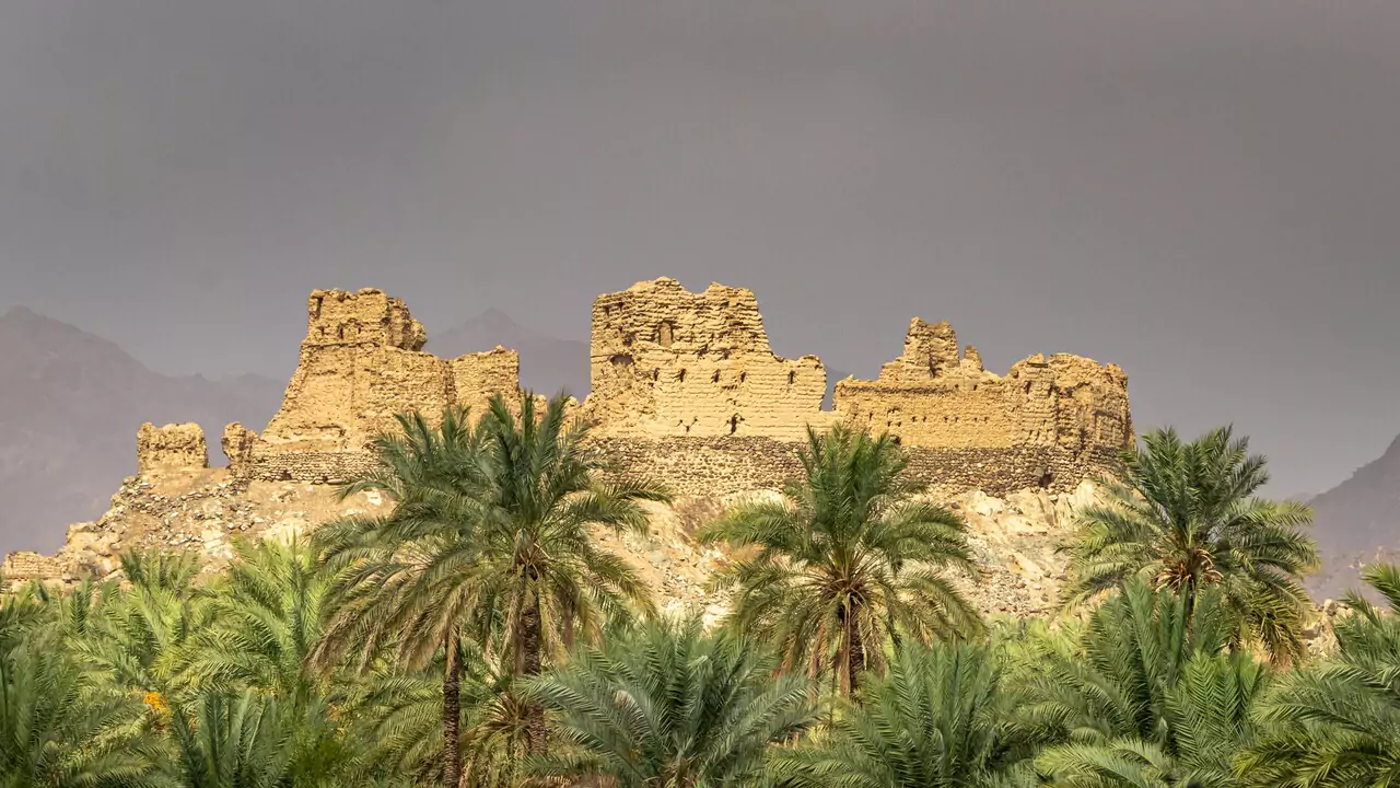 Desert landscape featuring the crumbling ruins of an ancient castle against a bright sky.