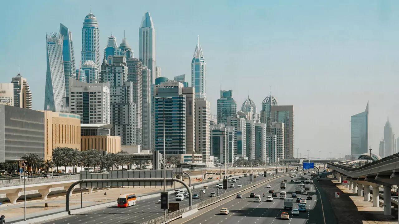 A highway perspective of the city, highlighting tall buildings against a sunny sky.