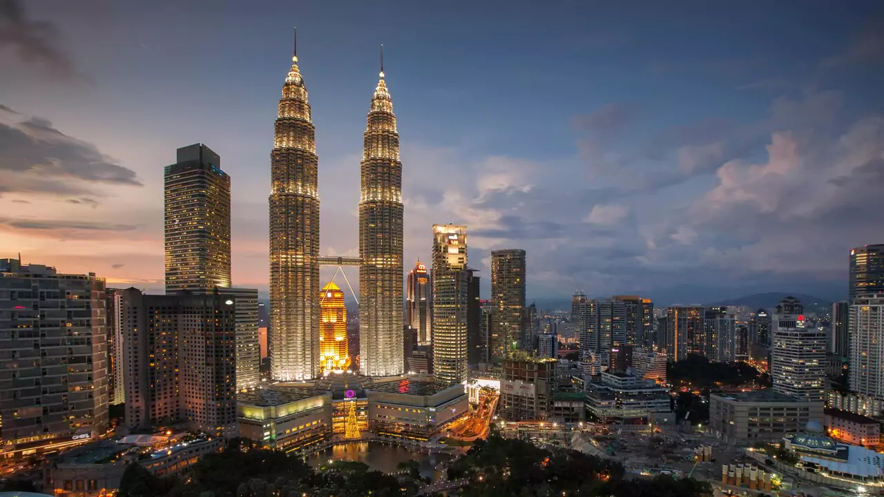 Petronas Towers at dusk in Kuala Lumpur, illuminated against a colorful sky.