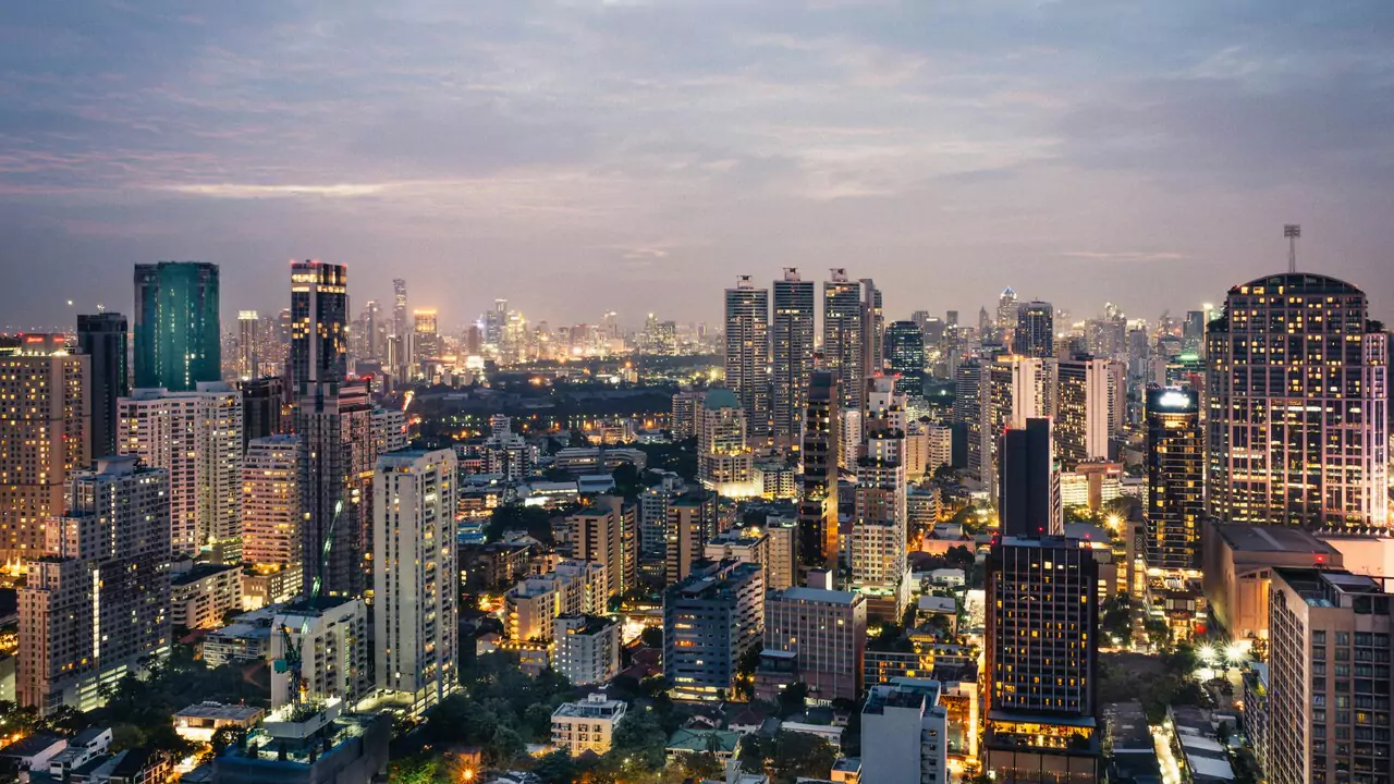 City skyline glowing at dusk, with buildings illuminated against a darkening sky.