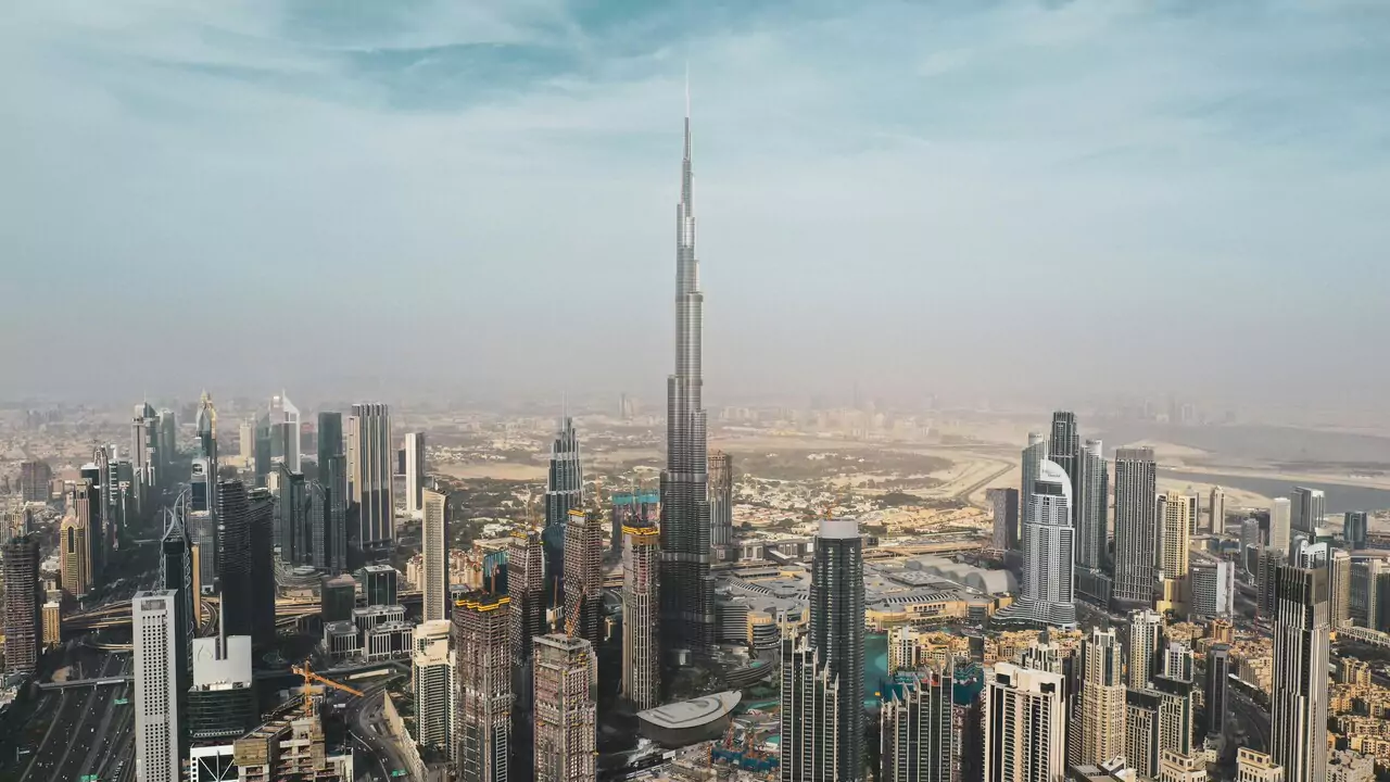 View of Dubai skyline from the top of Burj Khalifa, showcasing tall buildings and the cityscape under a clear blue sky.