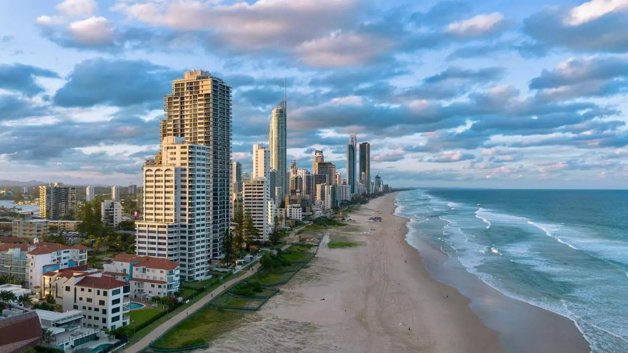 The skyline of Gold Coast at sunset, featuring skyscrapers outlined by colorful sky and calm waters.
