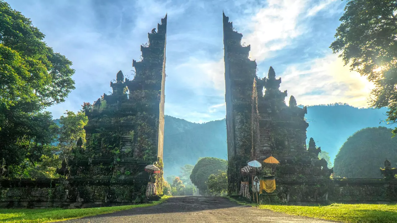 A beautiful temple entrance in Bali, adorned with detailed carvings and framed by lush vegetation.