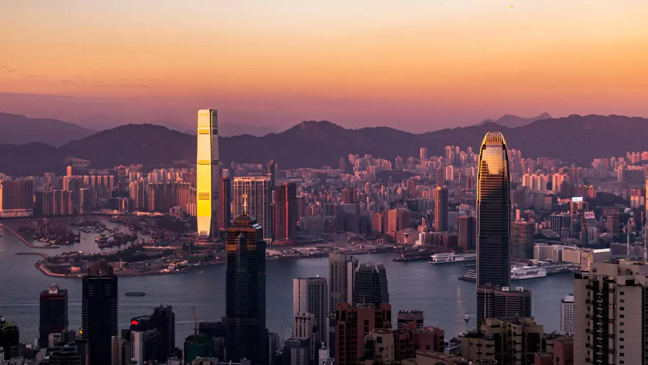 Sunset over Hong Kong skyline, showcasing skyscrapers outlined by vibrant colorful sky.