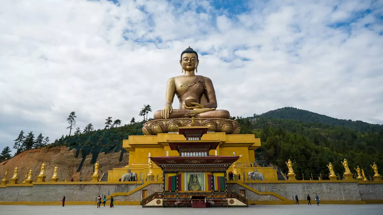 A golden Buddha statue stands prominently in the center of a spacious area.