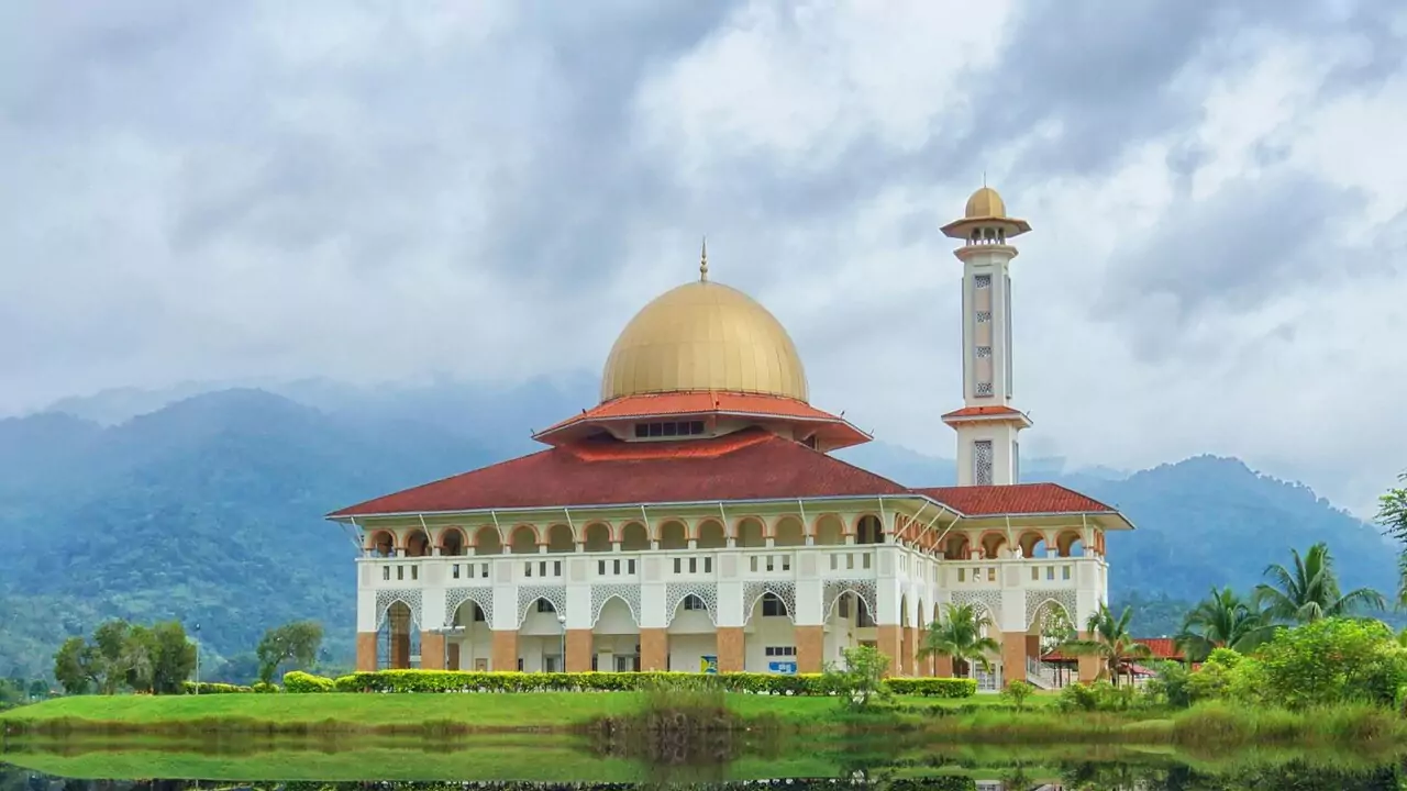 A serene mosque in a field, framed by mountains, creating a peaceful landscape.