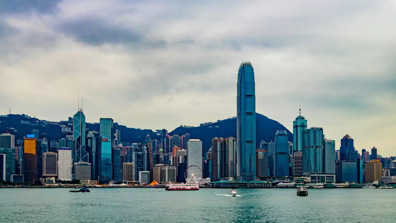 Hong Kong skyline featuring tall buildings and a vibrant cityscape against a clear blue sky.