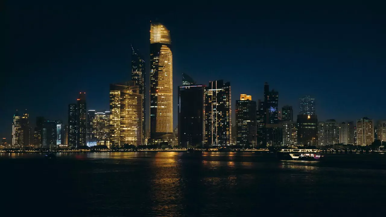 Night view of Abu Dhabi's skyline, showcasing bright buildings and a vibrant city atmosphere.