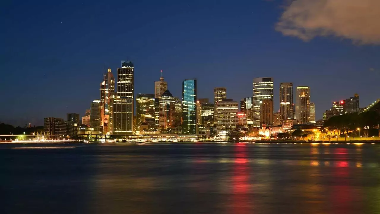 City skyline at night with bright lights reflecting on the calm water below.