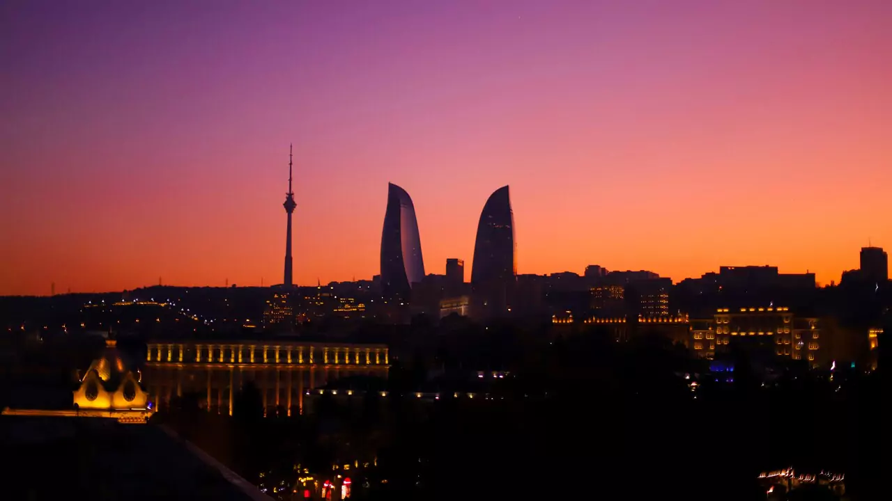 Sunset over Baku, casting its silhouette against a colorful sky filled with orange, pink, and purple tones.