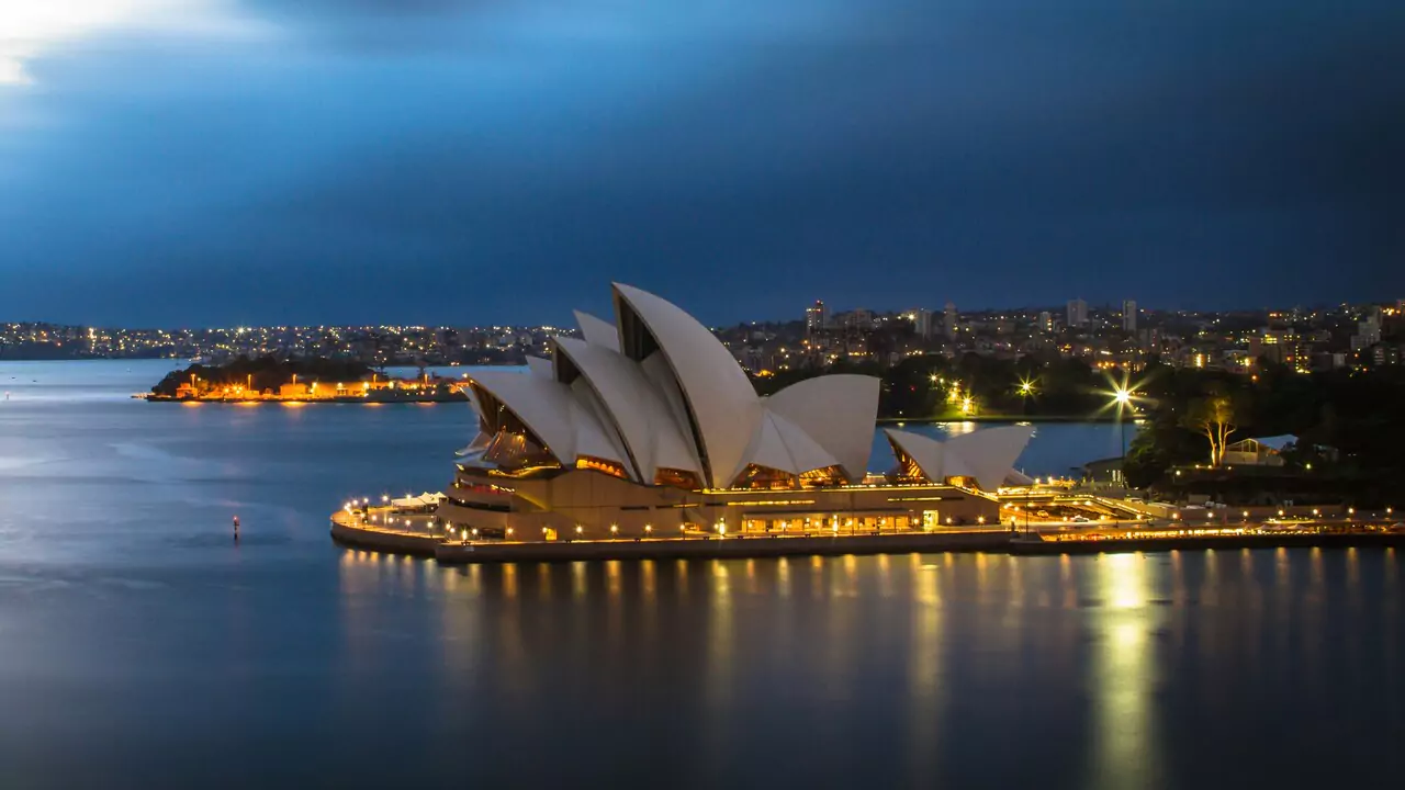 Sydney Opera House illuminated at dusk, showcasing its iconic sails against a colorful evening sky.