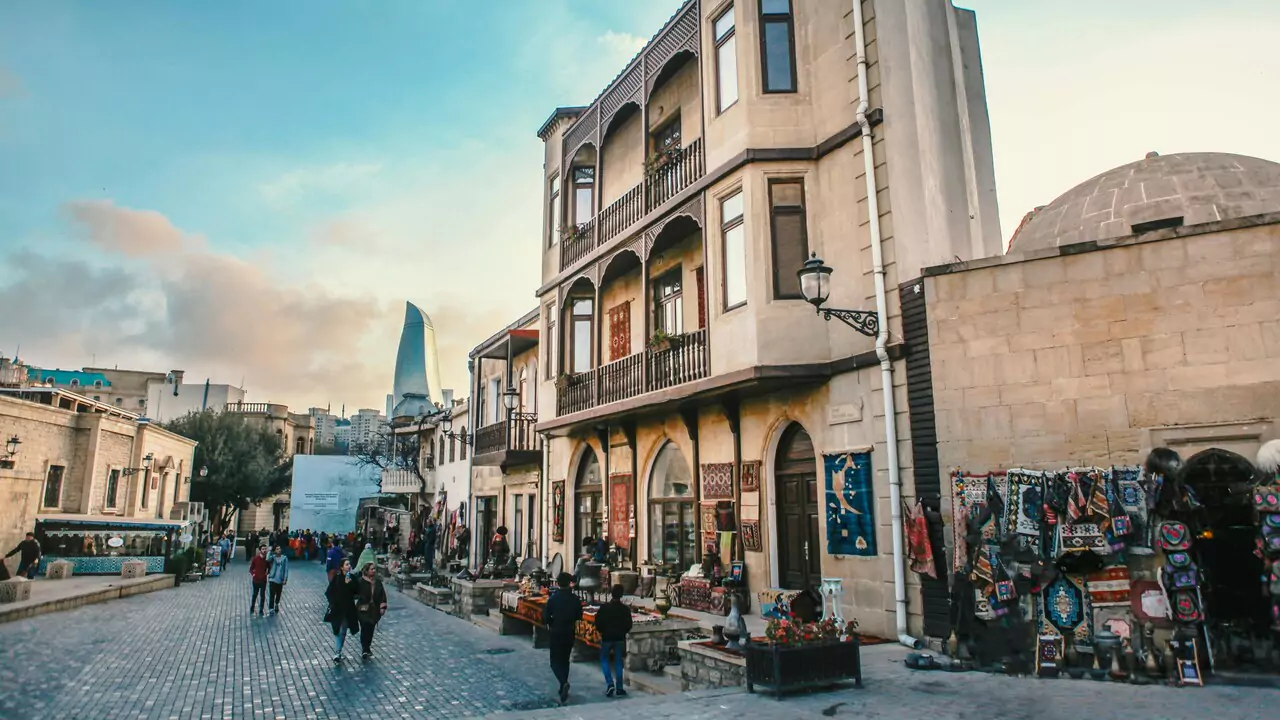 A narrow street in the old baku city, lined with traditional buildings and bustling with people.