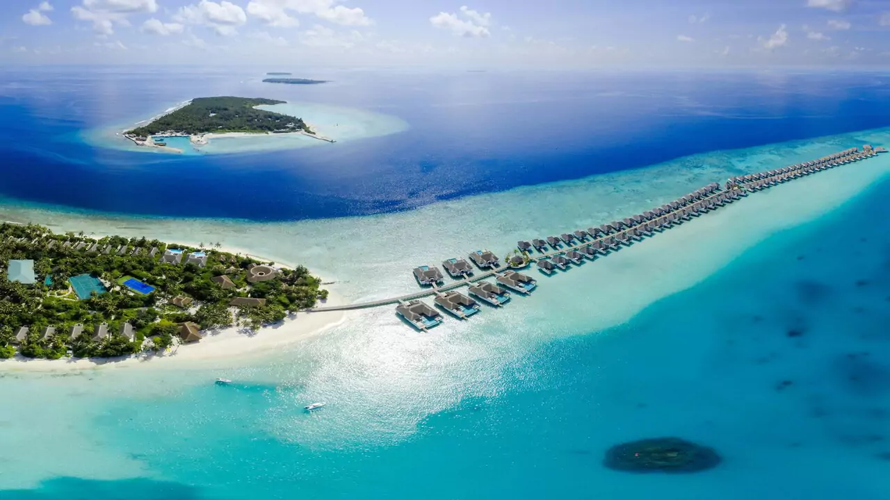 Bird's-eye view of an island with vibrant greenery, bordered by blue water, highlighting the serene environment.