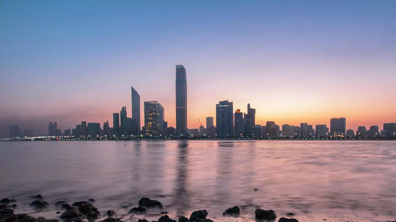 Abu Dhabi skyline at sunset, showcasing tall buildings silhouetted against a colorful sky.