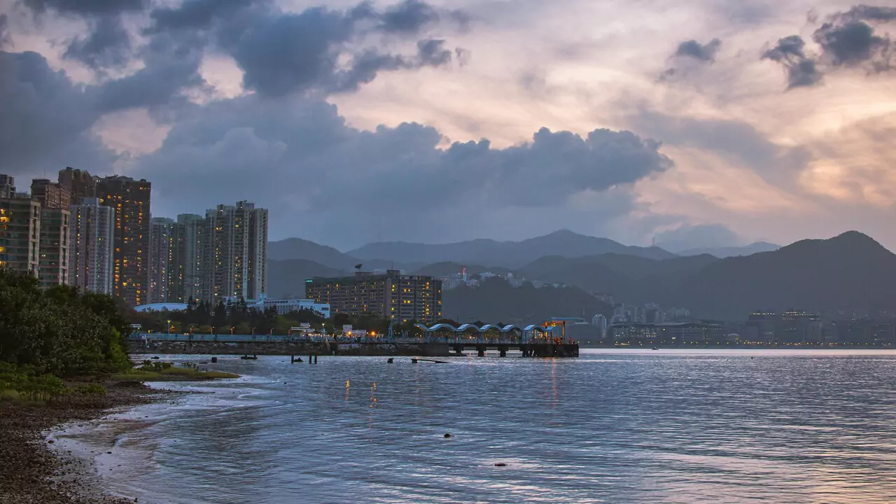 A picturesque cityscape at sunset, with mountains rising in the background.