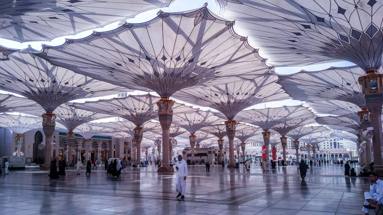 The Grand Mosque of Mecca, a large and sacred Islamic site, features a vast courtyard with large umbrellas.