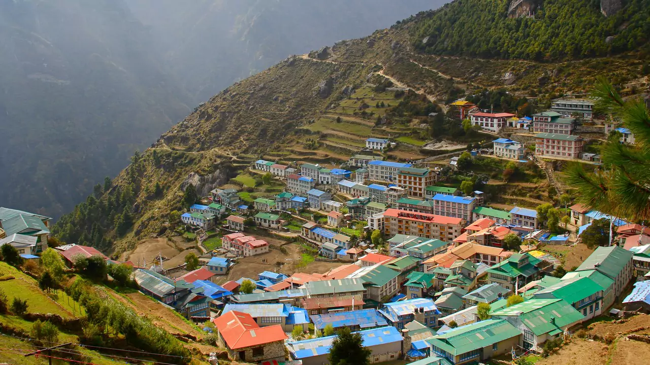 A charming village nestled in the mountains, showcasing houses with bright, colorful roofs under a clear blue sky.
