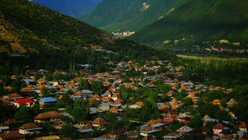 A charming mountain village with a cluster of houses set against a backdrop of towering peaks.