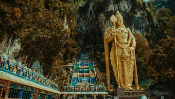 Murugan God statue is prominently placed on a mountain, offering a serene view of nature and the sky above.
