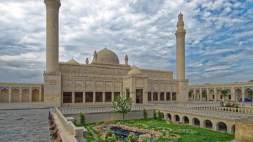 A mosque, featuring beautiful domes and elegant design, against a bright blue sky.