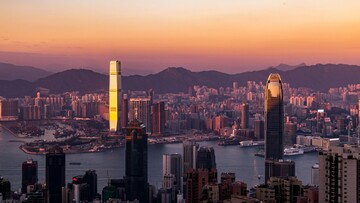 Sunset over Hong Kong skyline, showcasing skyscrapers outlined by vibrant colorful sky.