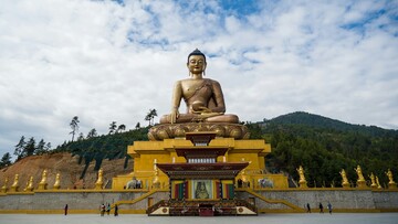 A golden Buddha statue stands prominently in the center of a spacious area.
