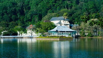 A large white building is located on the shore of a tranquil lake.