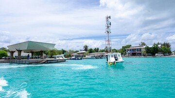 A boat moves smoothly on the water, close to a dock.