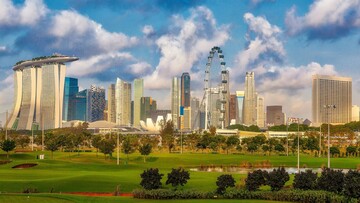 A vibrant golf course in Singapore, showcasing manicured greens, sand traps, and tropical trees.