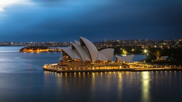 Sydney Opera House illuminated at dusk, showcasing its iconic sails against a colorful evening sky.