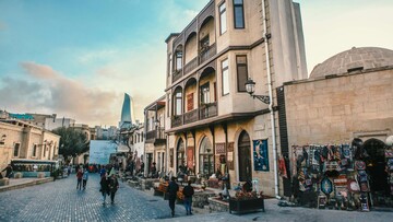 A narrow street in the old baku city, lined with traditional buildings and bustling with people.