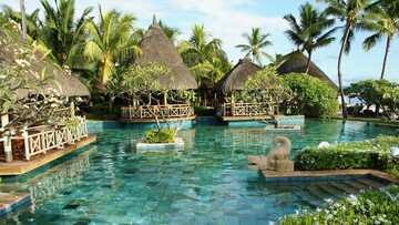 A relaxing resort scene showcasing a pool and cozy thatched huts amidst vibrant greenery.