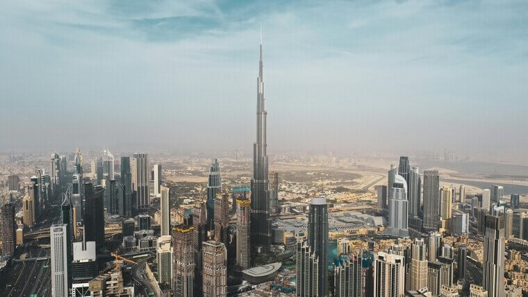 View of Dubai skyline from the top of Burj Khalifa, showcasing tall buildings and the cityscape under a clear blue sky.