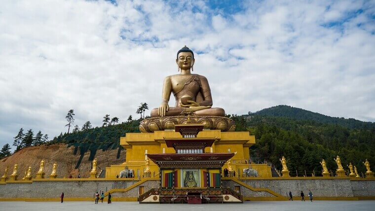 A golden Buddha statue stands prominently in the center of a spacious area.