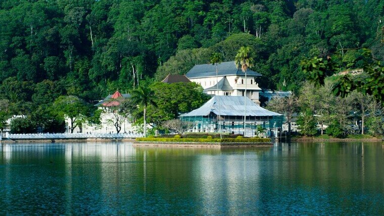 A large white building is located on the shore of a tranquil lake.