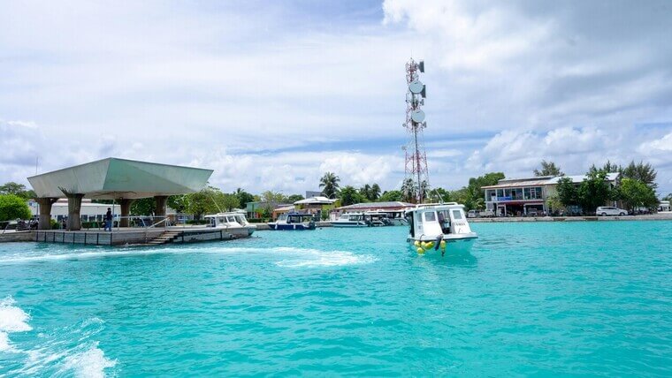 A boat moves smoothly on the water, close to a dock.