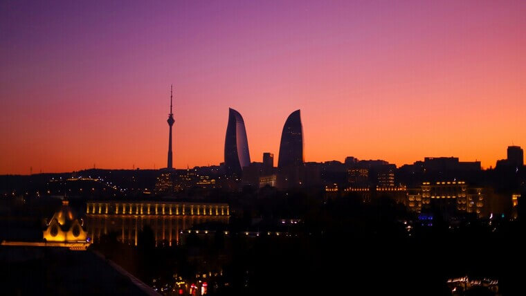 Sunset over Baku, casting its silhouette against a colorful sky filled with orange, pink, and purple tones.