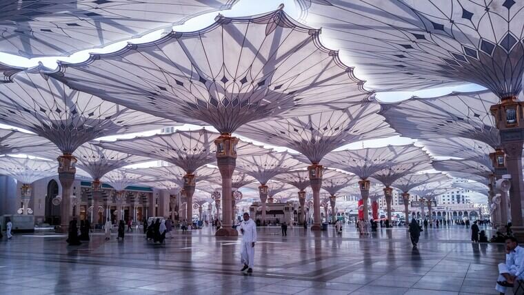 The Grand Mosque of Mecca, a large and sacred Islamic site, features a vast courtyard with large umbrellas.
